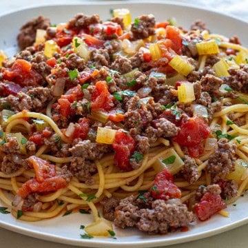 Chunky tomato sauce over spaghetti on a white plate.