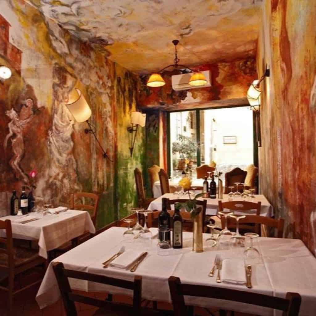 Interior view of the beautiful artistry on the trattoria walls, tables with white table cloths, cozy ambiance