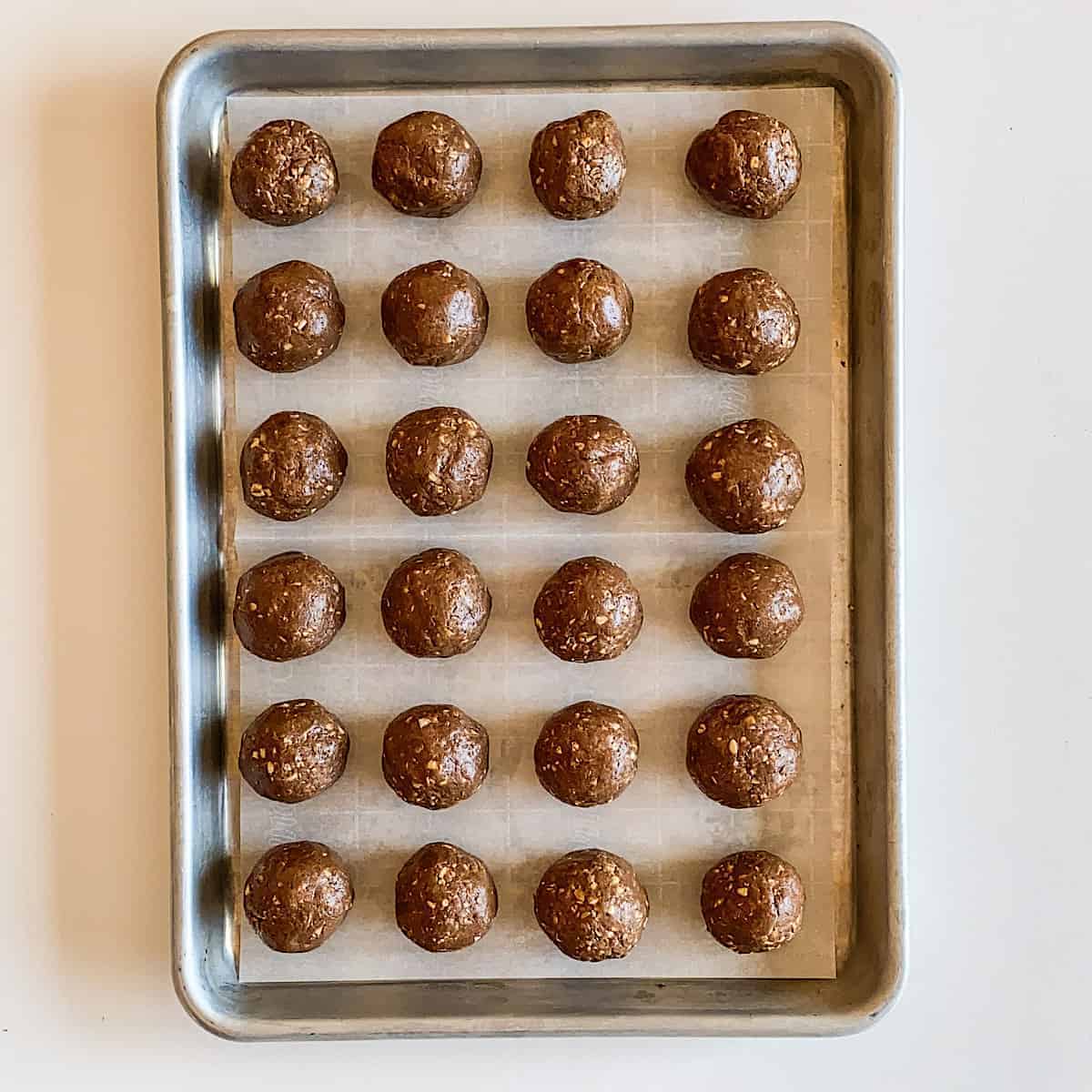 Bite sized balls drizzled with chocolate with chocolate chips sprinkled on white plate on light blue linen napkin.