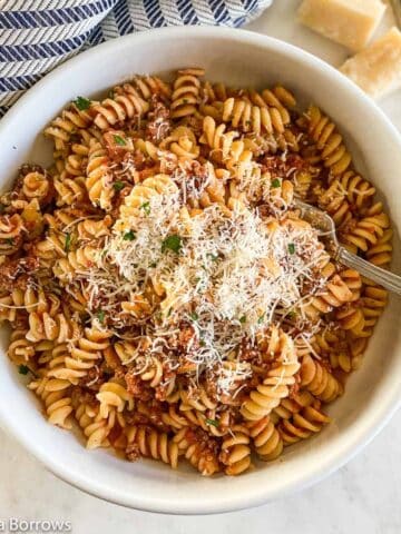 Easy weeknight dinner of Ground Bison Pasta made with rotini pictured in a white bowl, topped with freshly grated Parmigiano-Reggiano.