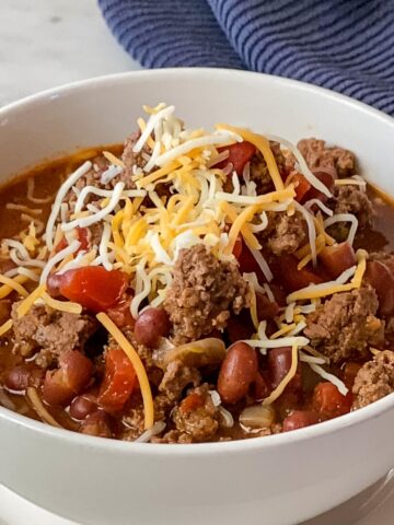 Bowl of Ground Bison Chili Recipe with a navy colored napkin in upper right corner.