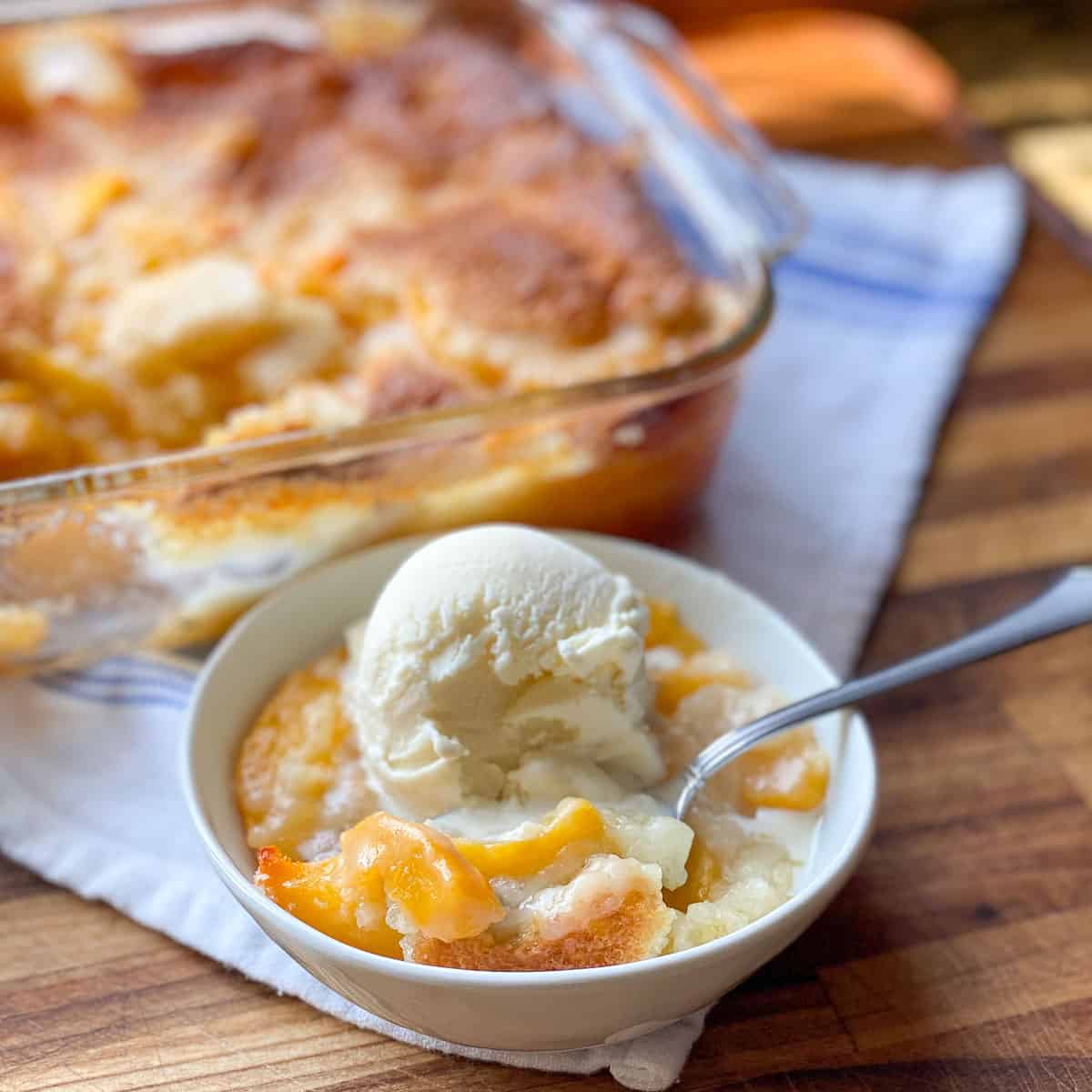 Image of a bowl of the Best Peach Cobbler with vanilla ice cream.
