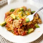 White plate full of Instant Pot Mexican Casserole with topped with fresh avocado.