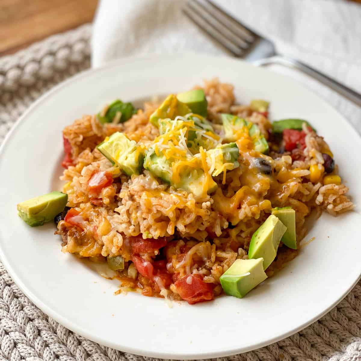 White plate full of Instant Pot Mexican Casserole with topped with fresh avocado.