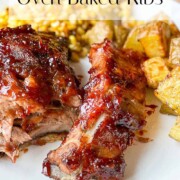 Oven Baked Ribs served on a white plate with Fried Corn and Roasted Potatoes.