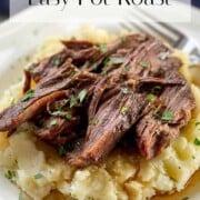 Tender pot roast on creamy mashed potatoes with savory gravy on a white dinner plate.