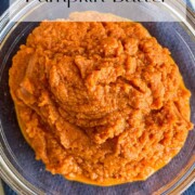 Pumpkin butter in a glass bowl sitting on a blue kitchen towel.