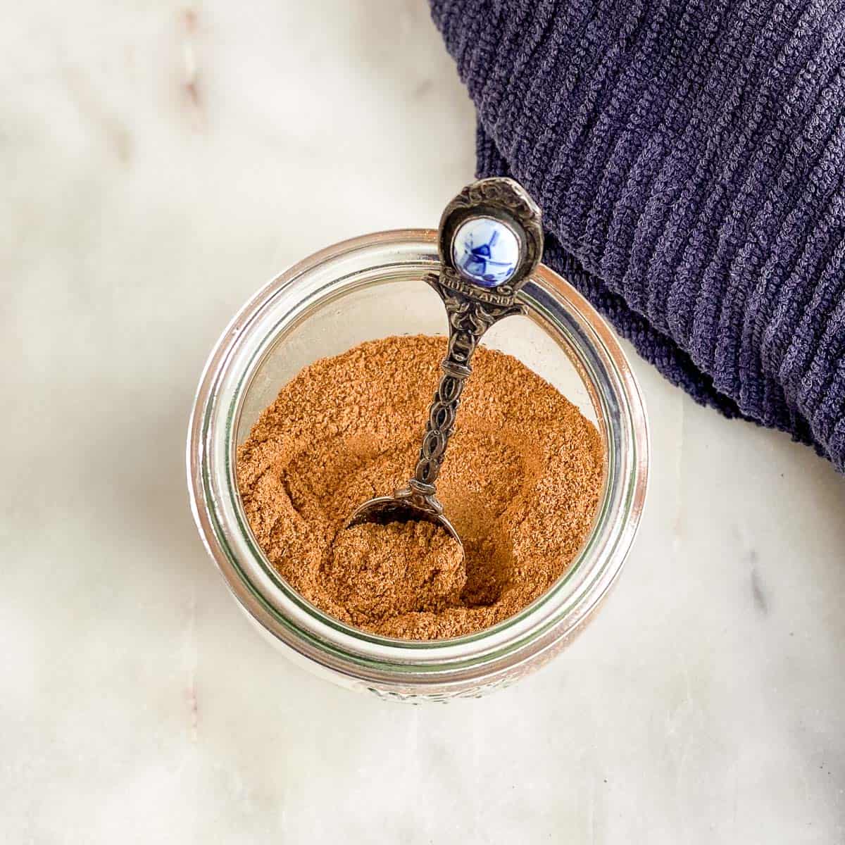 Overhead shot of pumpkin spice in clear jar with antique spoon.