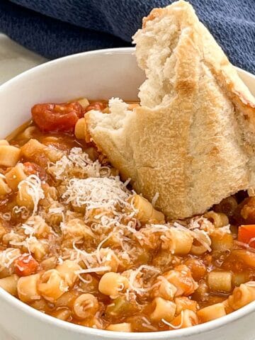Image of a bowl of Pasta Fagioli with a hunk of bread.