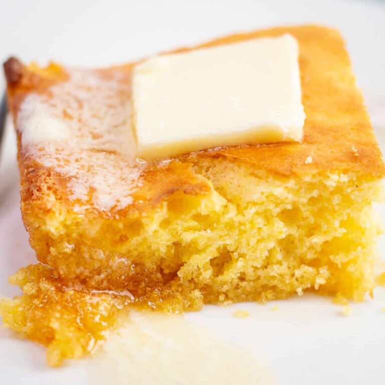 A square of honey butter cornbread with a tab of butter on top.