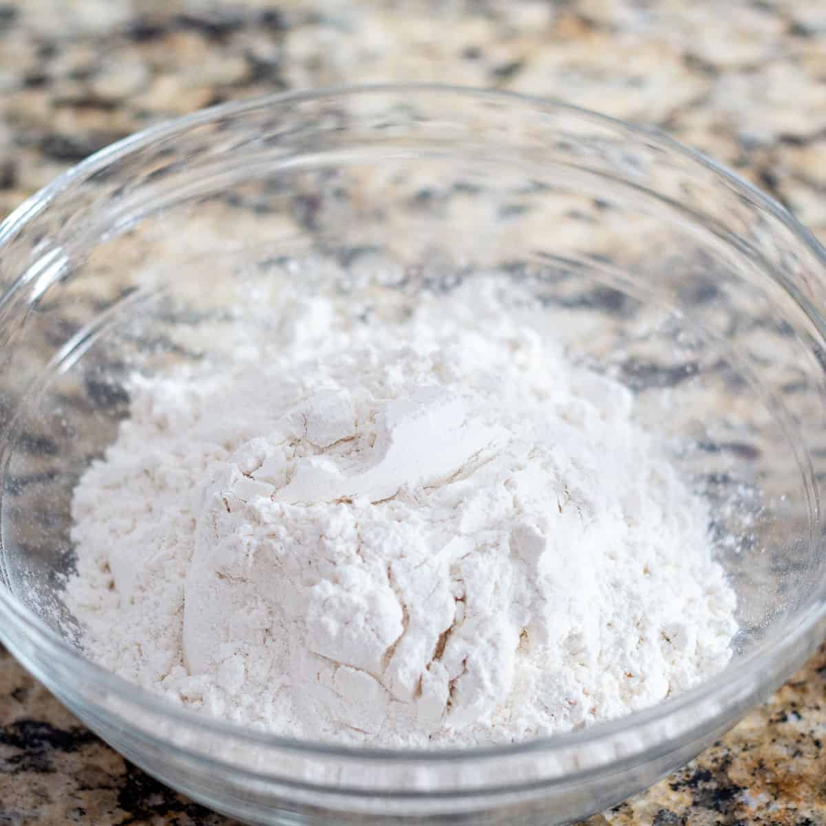 Sifted flour, baking soda, and salt in a clear glass bowl. 