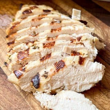 Sliced grilled chicken on a cutting board.