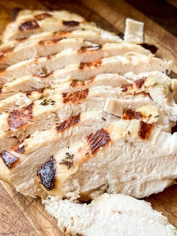 Sliced grilled chicken on a cutting board.