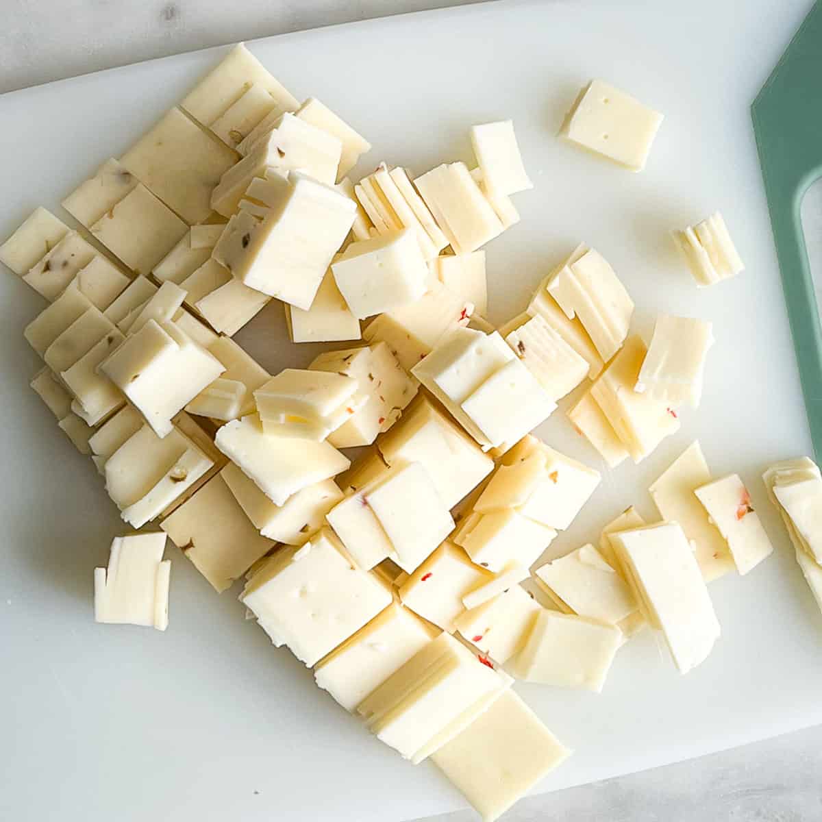 Diced cheese on a white cutting board.