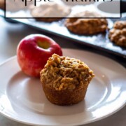 Apple Cinnamon Muffin and a red apple on a white plate with a muffin tin of apple muffins in upper right corner with a title banner across the top.