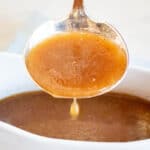 Pan Gravy dripping from ladle into white gravy boat.