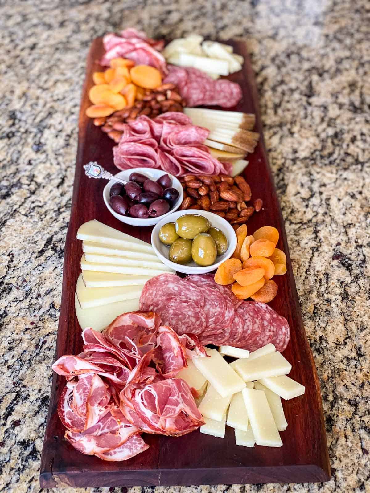 Charcuterie board full of a variety of meats, cheeses, and nibbles.