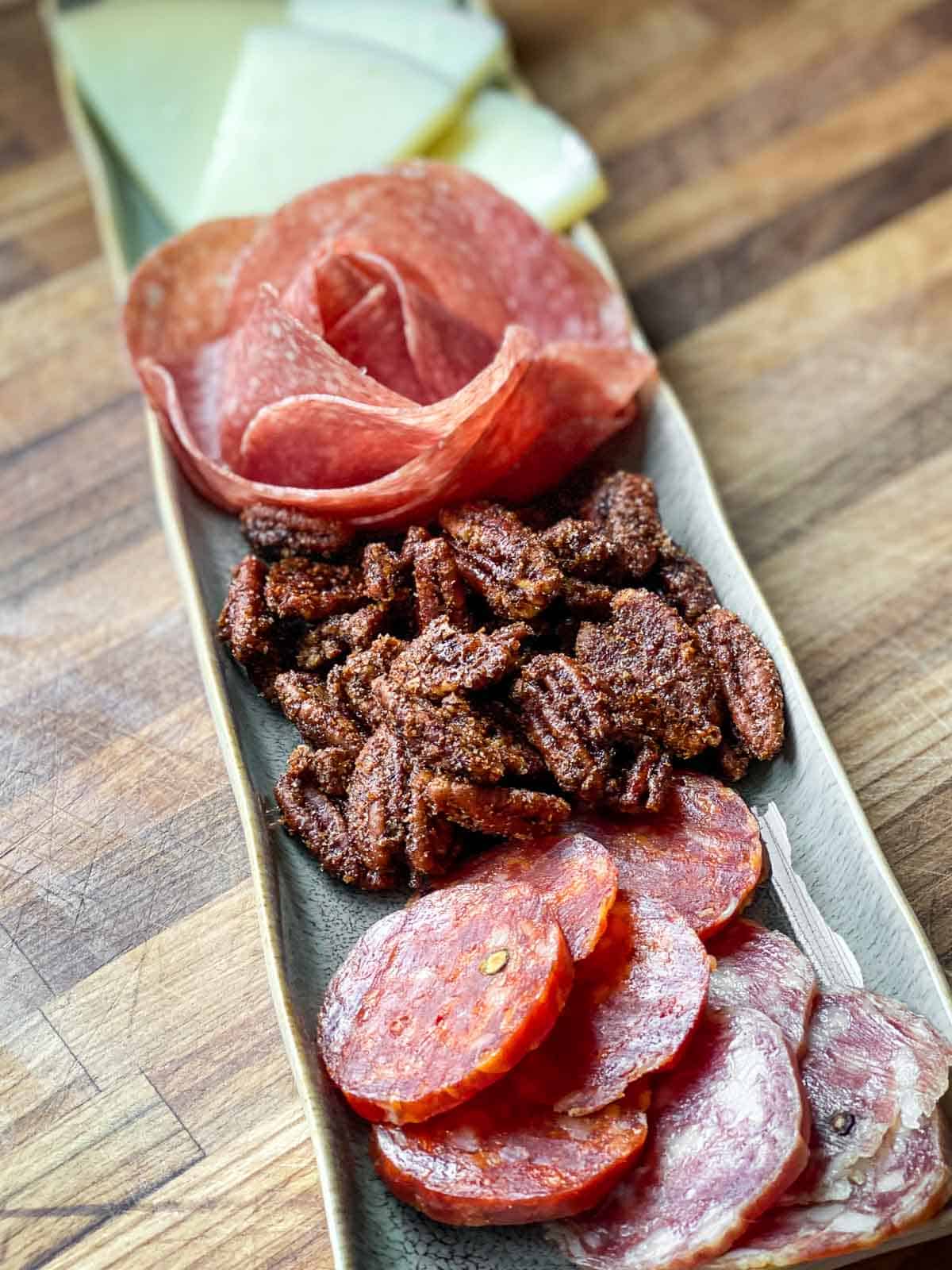 Charcuterie board full of a variety of meats, cheeses, and nibbles.