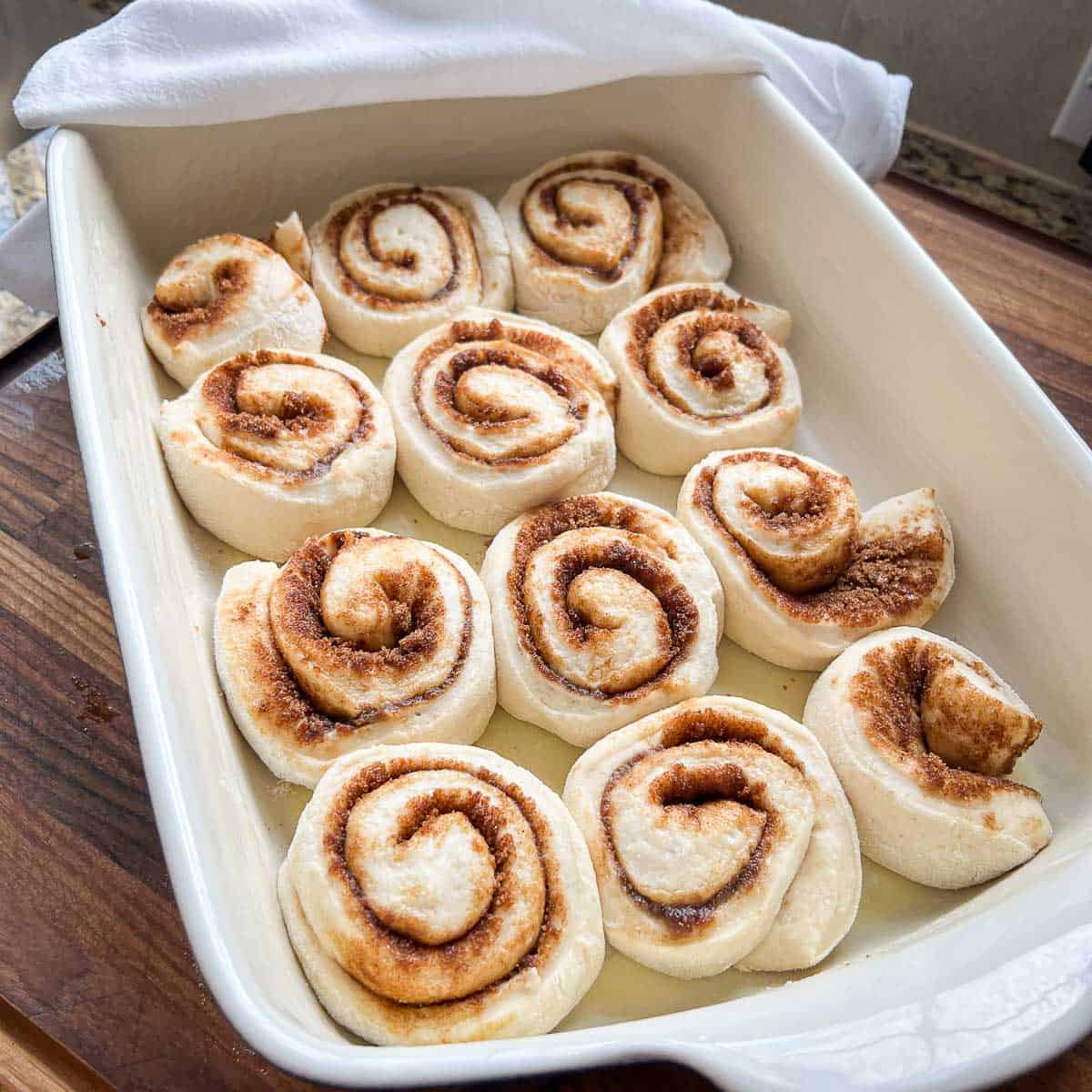 Risen cinnamon rolls in a baking dish.