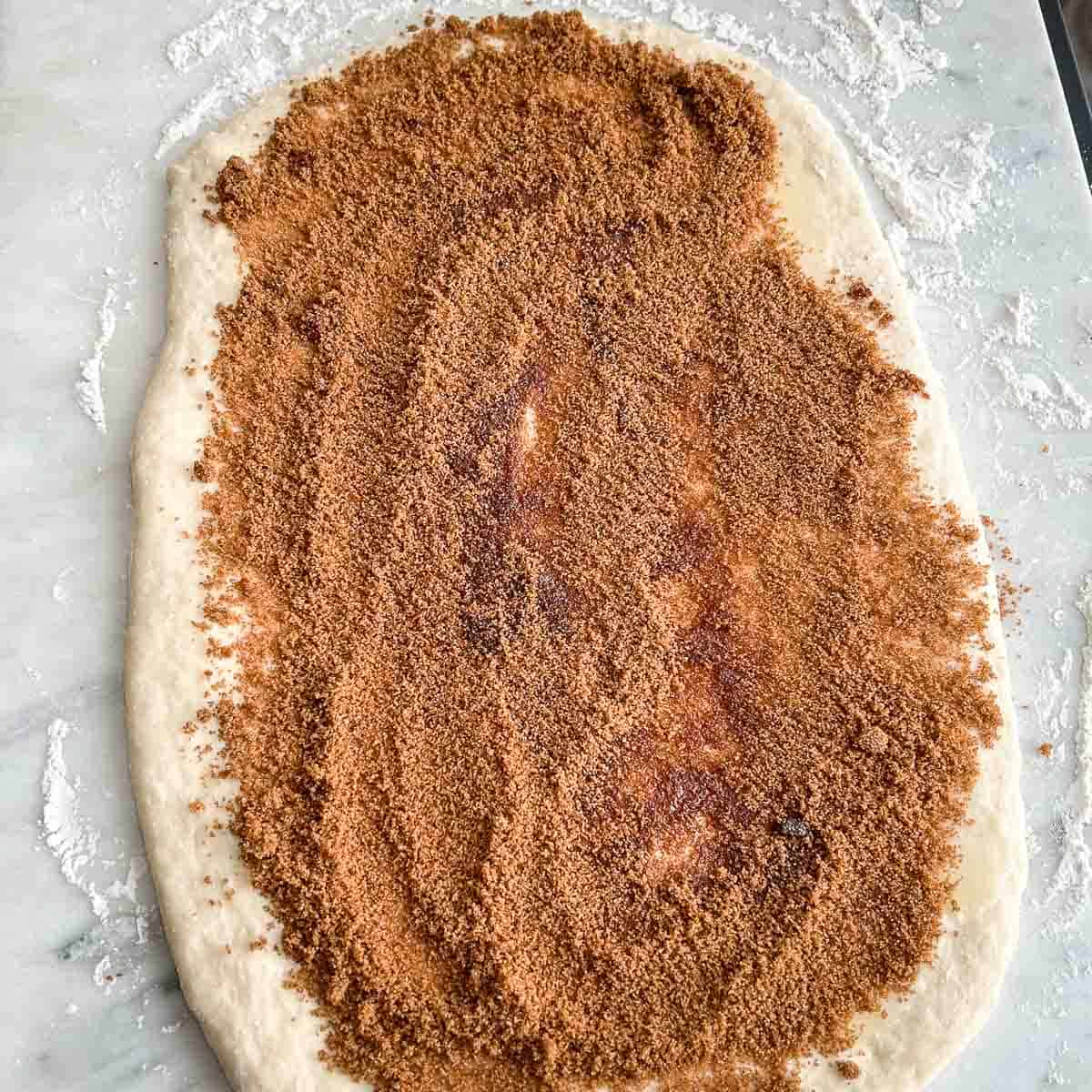 Cinnamon roll filling spread out on top of rolled out dough.