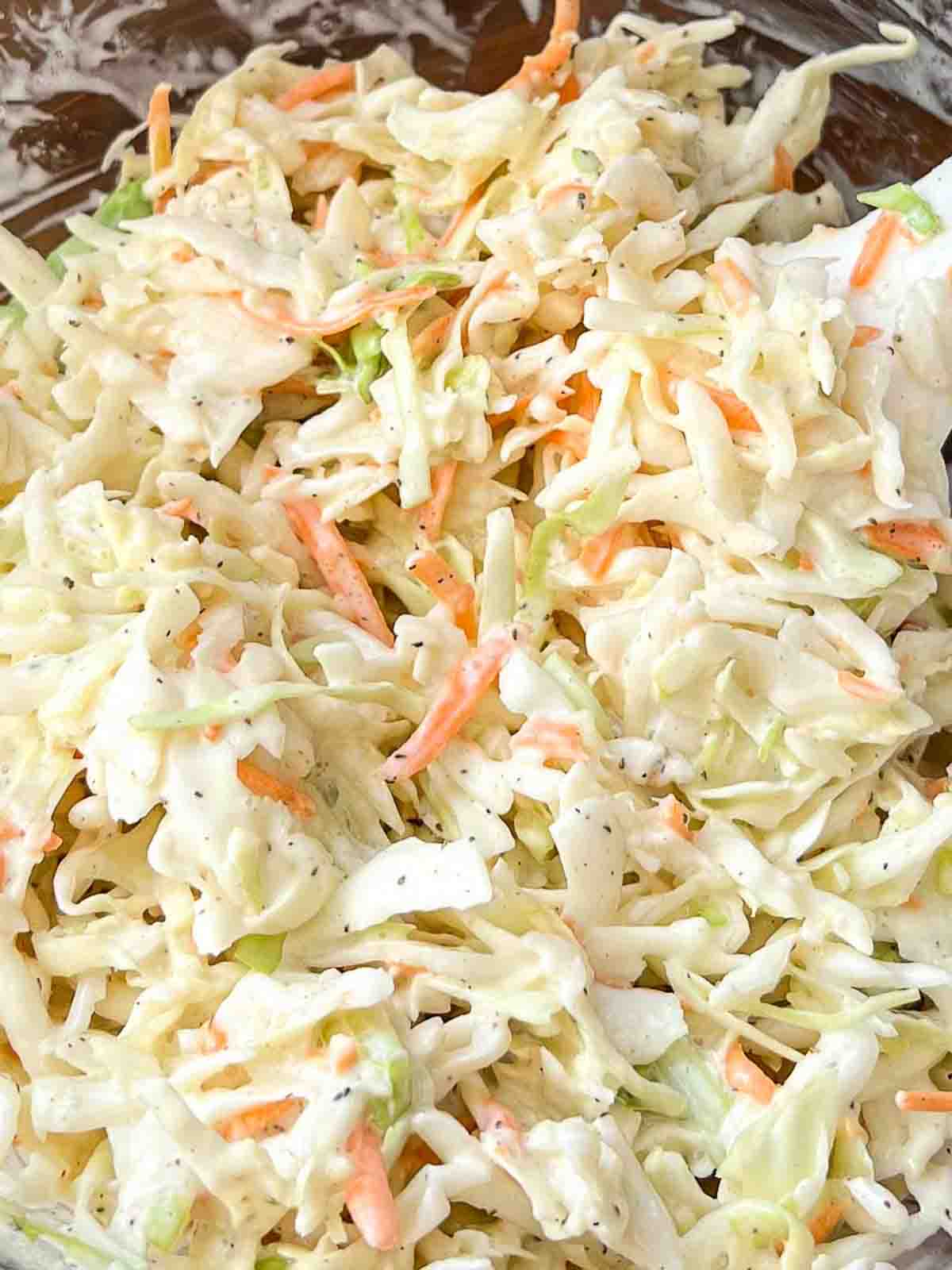 Creamy coleslaw served in a white bowl with flecks of carrot and cabbage, ready for BBQ pulled pork.