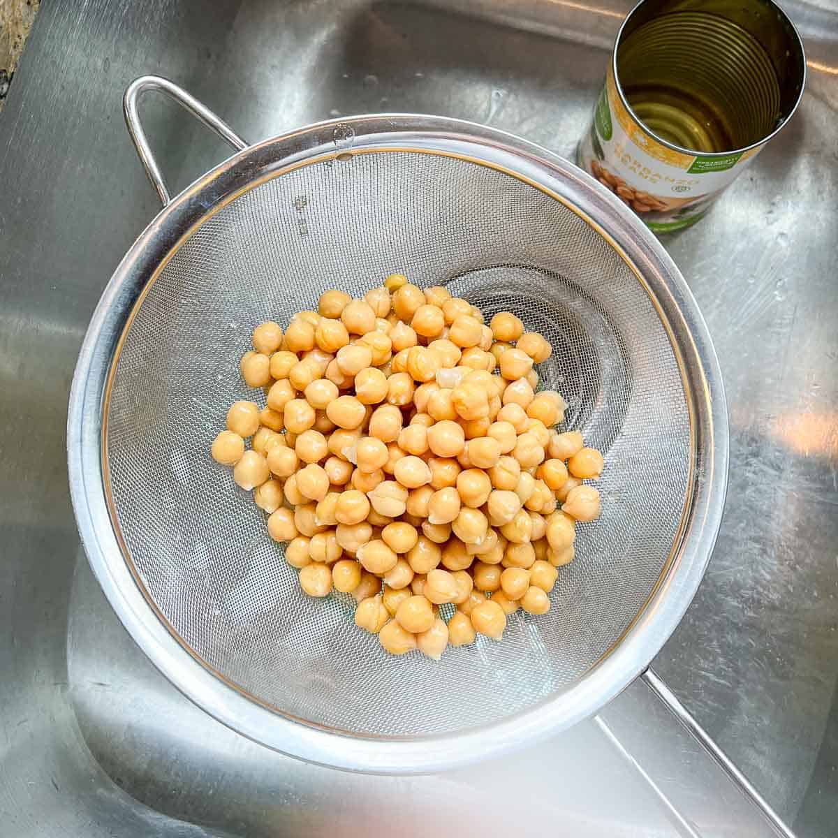 Chickpeas in a strainer over a sink.