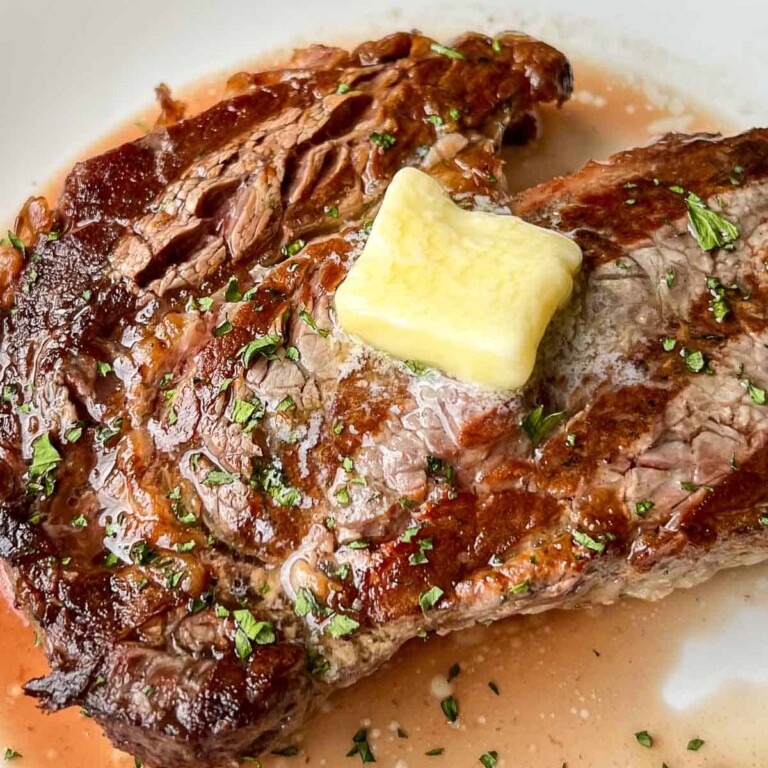 A grilled ribeye steak with a tab of butter on top.