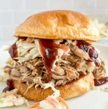 Pulled pork on a brioche bun with coleslaw and BBQ sauce dripping down the side.