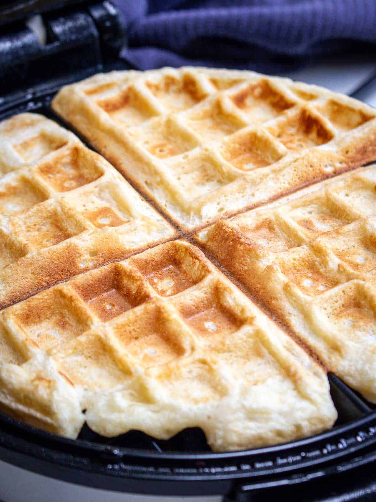 A homemade waffle ready to be taken out of the waffle iron.
