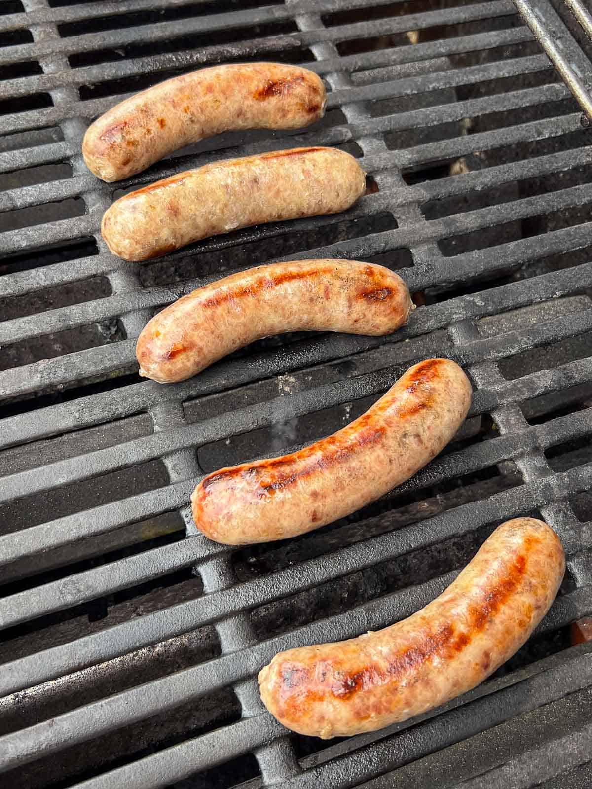 5 brats with grill marks on the grill.