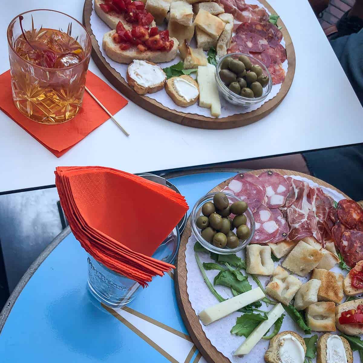 Aperitivo in Laguria, Italy with two platters of focaccia and various meats and cheeses.