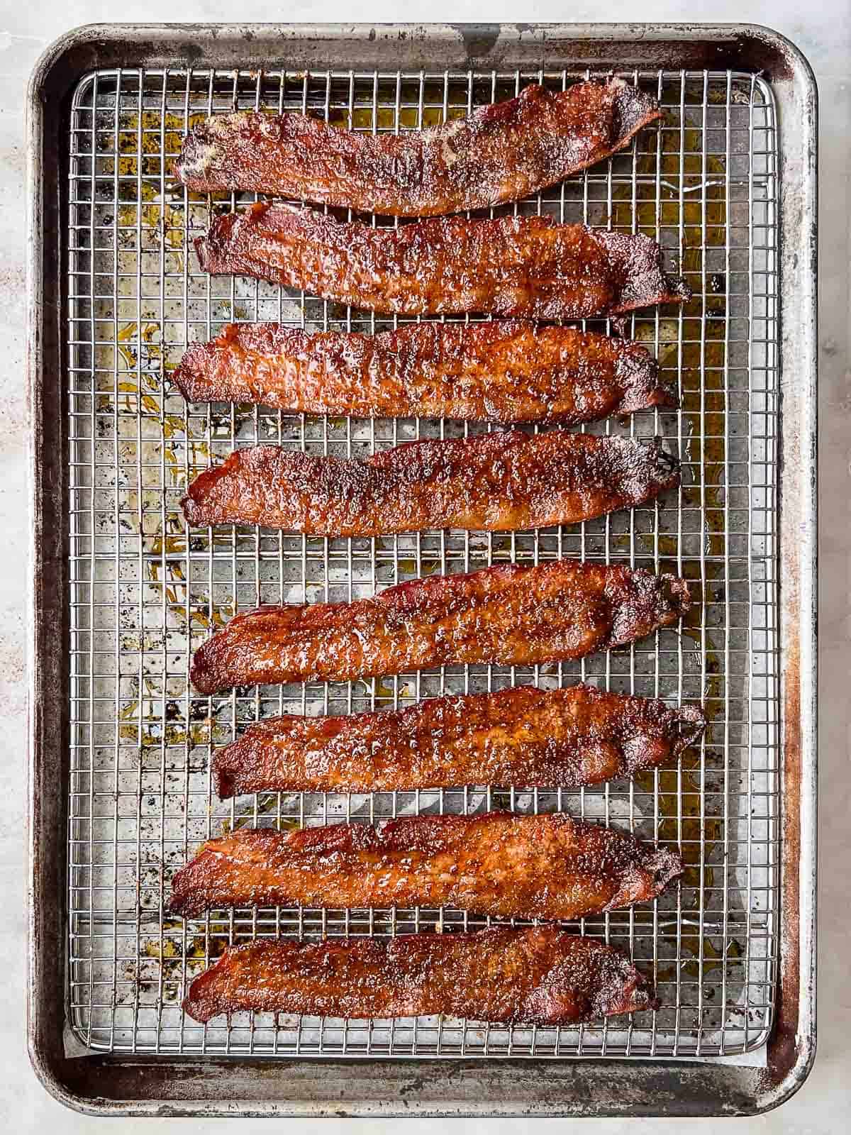Slices of candied bacon on a backing rack.