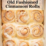 A pan of old fashioned cinnamon rolls with cream cheese frosting drizzled over the top.