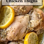 Baked chicken thighs with lemon slices in a white dish.
