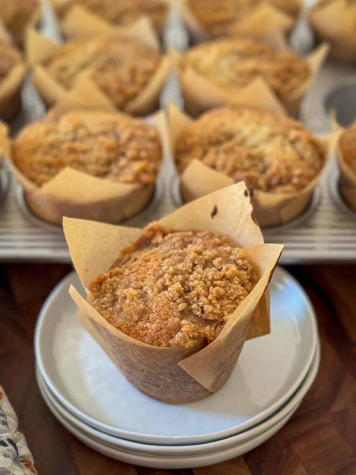 Banana Muffin on a white plate with a muffin tin of same in background.