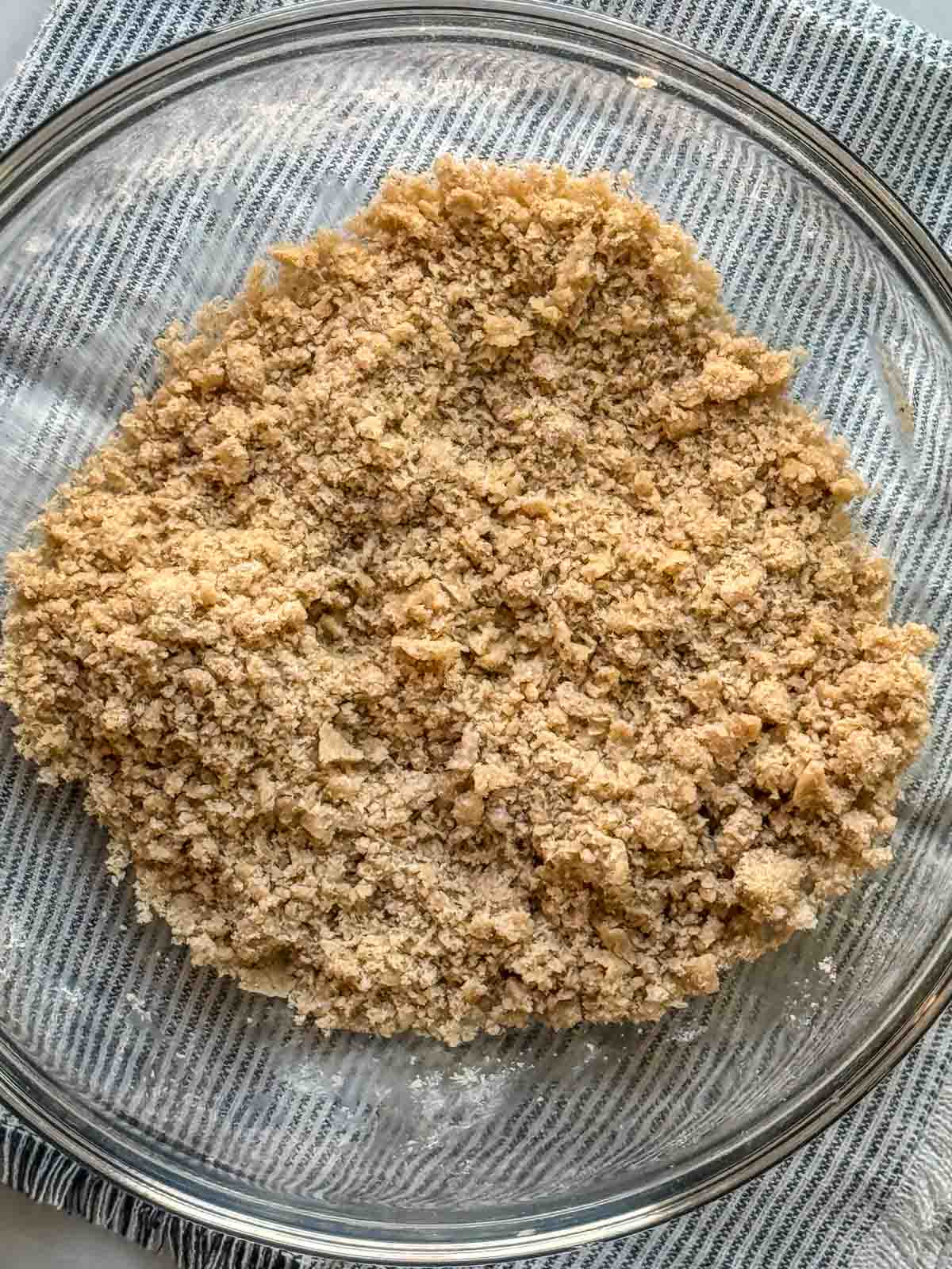 Streusel Topping in a clear glass bowl with a striped napkin underneath.