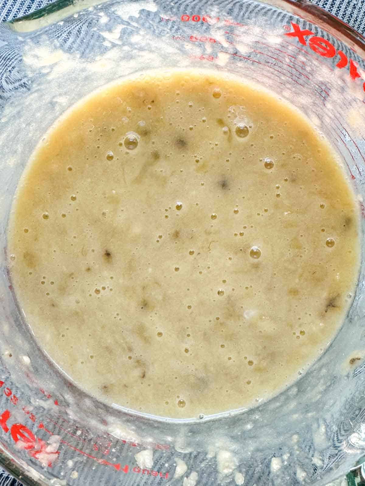 Wet ingredients for banana muffins in a clear measuring cup.