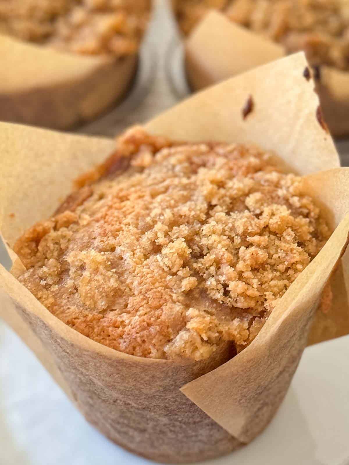 Banana Muffin on a white plate with a muffin tin of same in background.