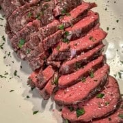 Sliced slow roasted beef tenderloin aserved on a platter.