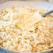 A bowl full of creamy parmesan risotto garnished with shavings of parmesan cheese.