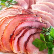 Slices of Honey Baked Ham fanned out on a platter garnished with parsley sprigs.