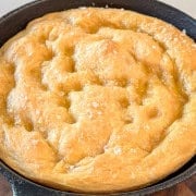 A whole baked focaccia in a cast iron skillet.
