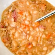 Leftover ham and bean soup served in a stoneware bowl with a silver spoon.