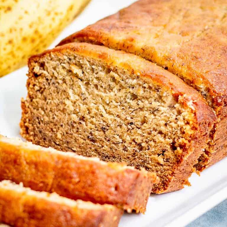 A loaf of sliced banana bread on a white plate.