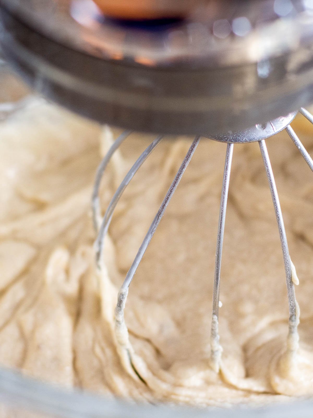 A mixer is mixing batter in a glass bowl.