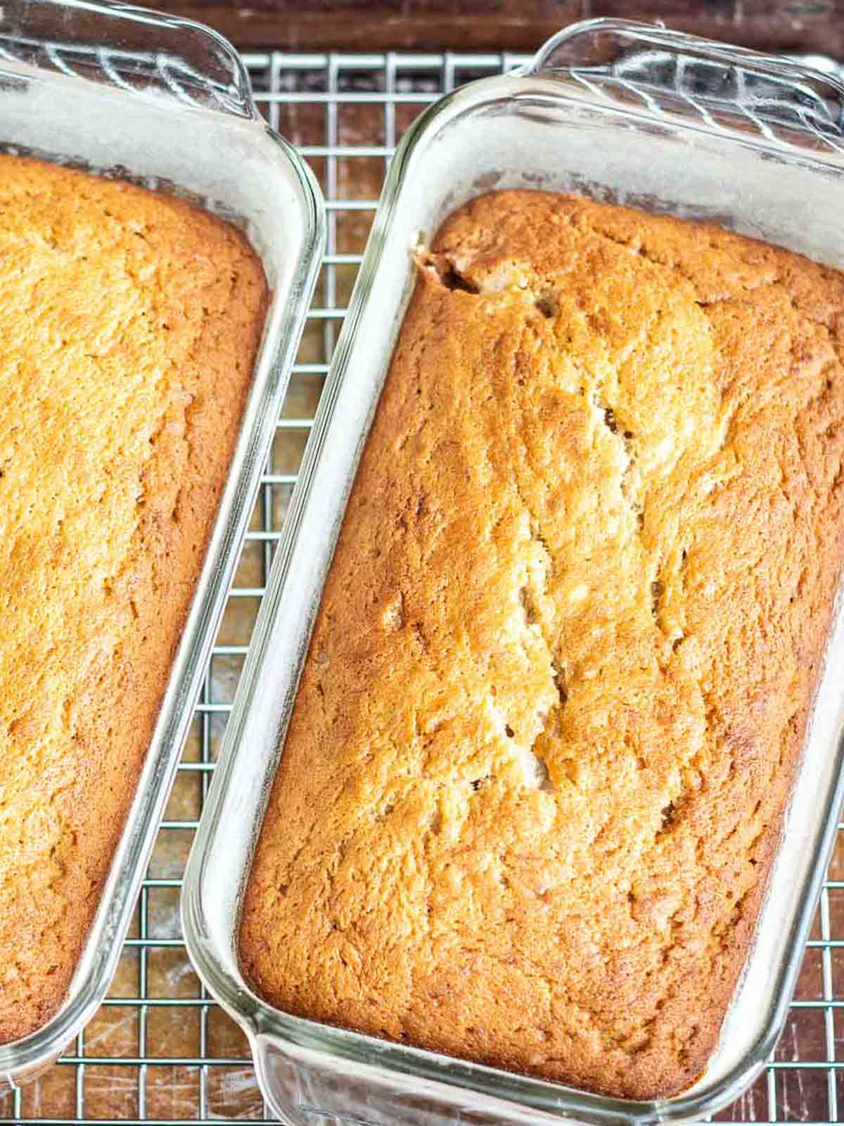 Two loafs of banana bread sitting on a cooling rack.