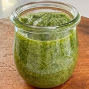 An open jar of homemade basil pesto to show flecked texture.