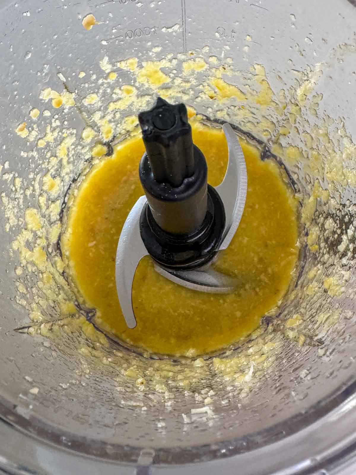 Blended pine nuts, garlic, Parmesan, and olive oil in a blender for homemade basil pesto.