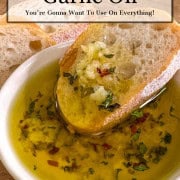 Crusty bread dipped into small dish of garlic oil recipe with herbs.