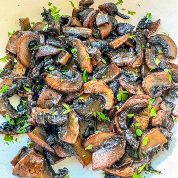 Golden saut&eacute;ed mushrooms with fresh parsley garnish.